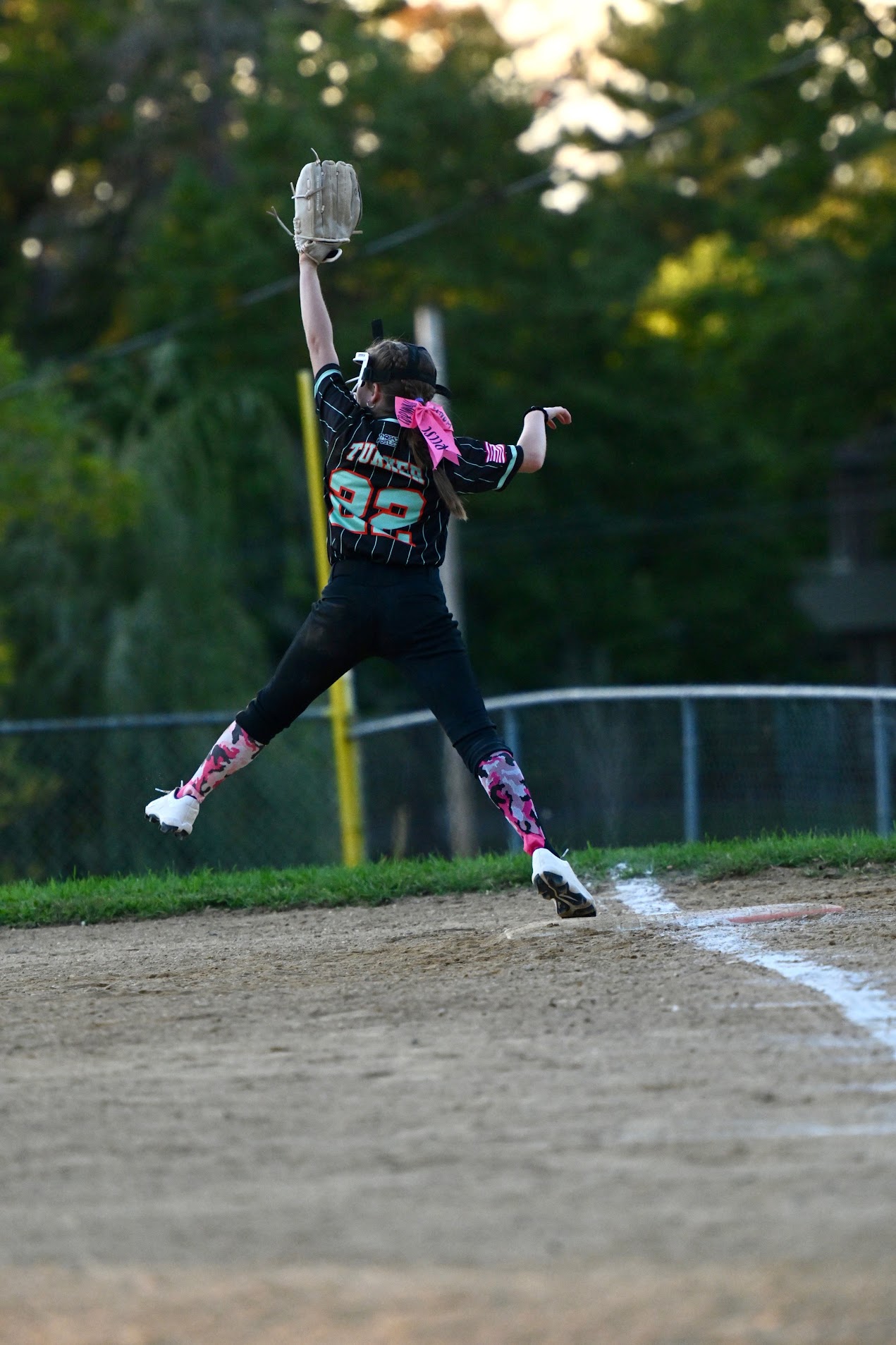 Reese in mid air at first base reaching up for a high throw.