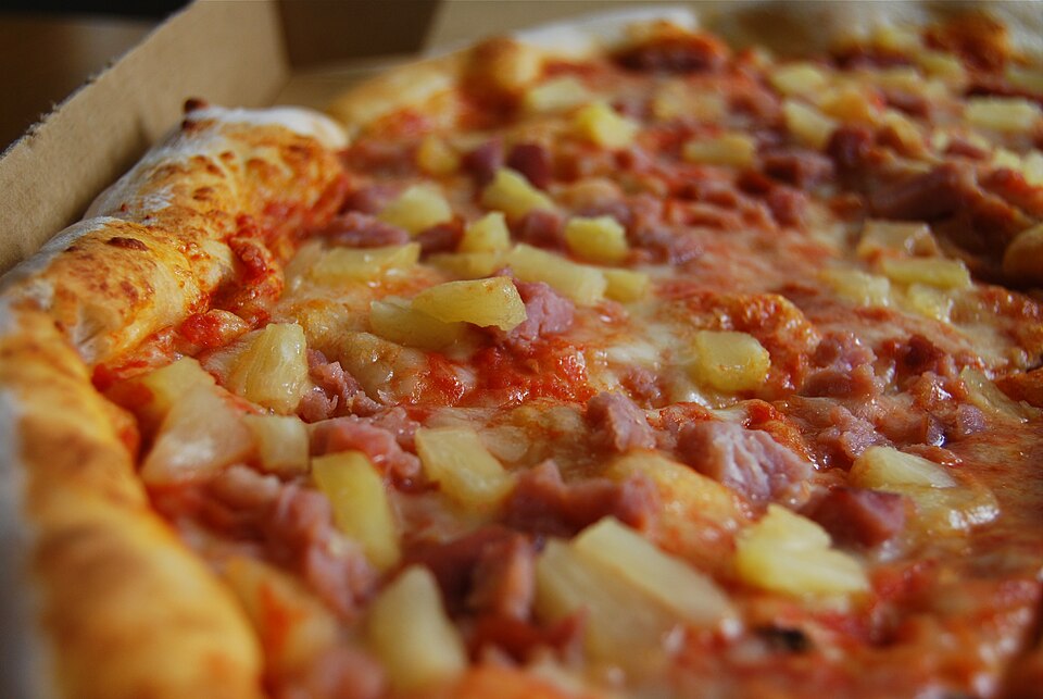 A ham and pineapple pizza in a box.
